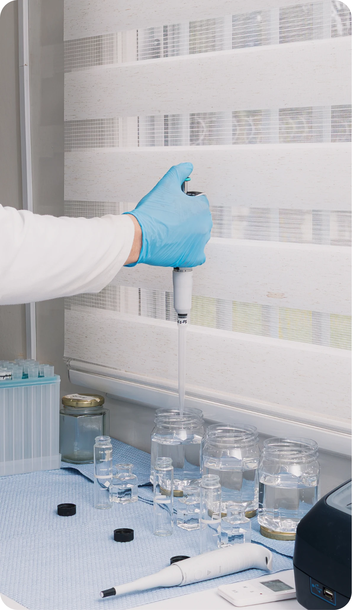 Analista de laboratorio pipeteando muestras en frascos de vidrio
